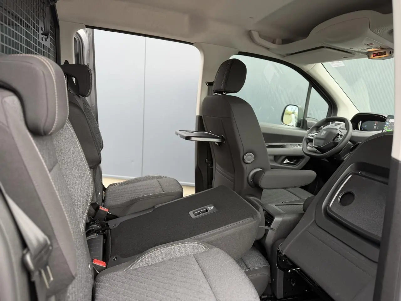 Vue intérieure côté droit du Peugeot Rifter gris acier 2026, montrant les sièges individuels et la tablette rabattable.