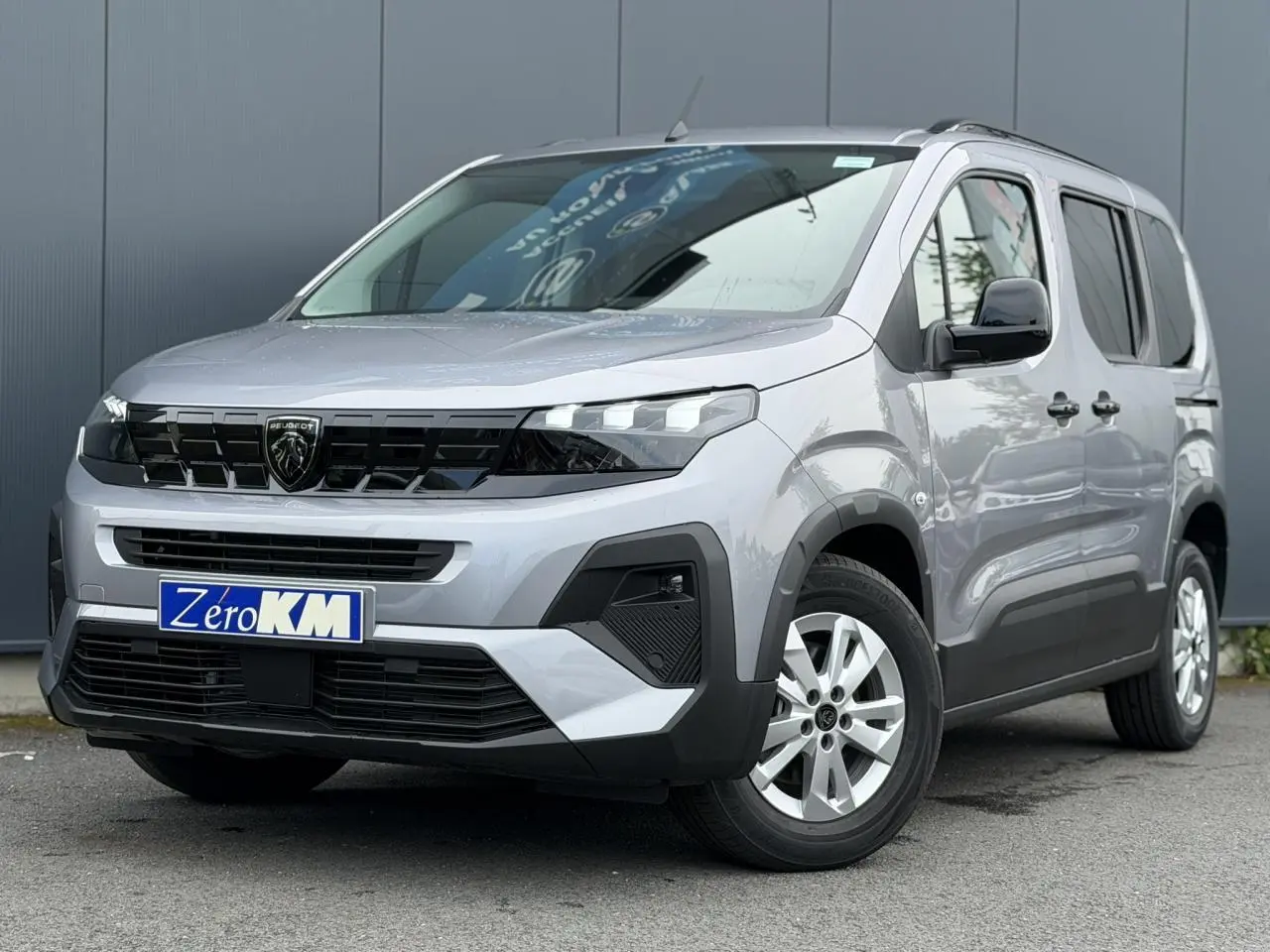 Peugeot Rifter gris acier en 3/4 avant droit, avec calandre noire et jantes alu 16 pouces visibles.