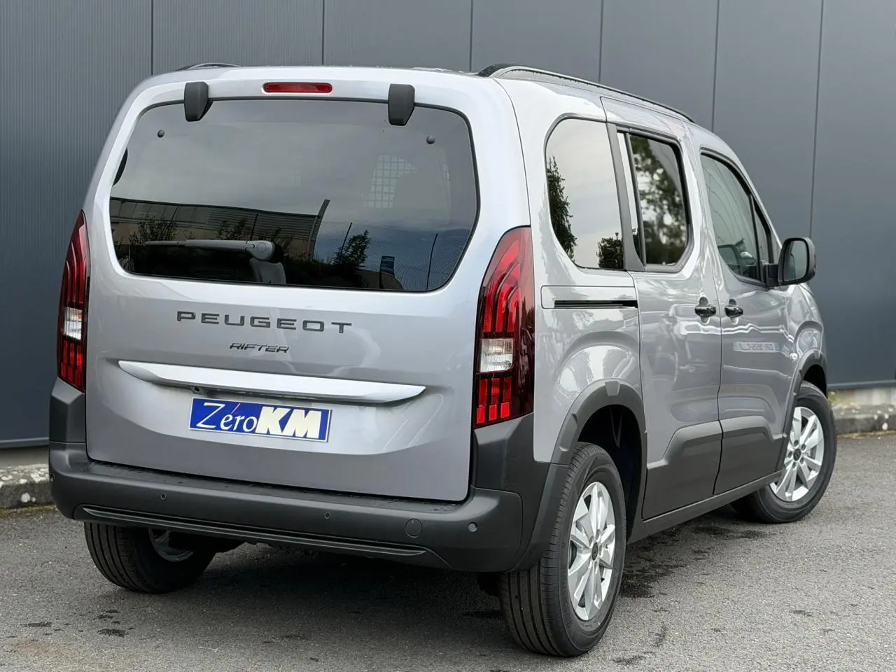 Vue 3/4 arrière droite du Peugeot Rifter gris acier 2026 avec portes latérales coulissantes et feux arrière LED distinctifs.