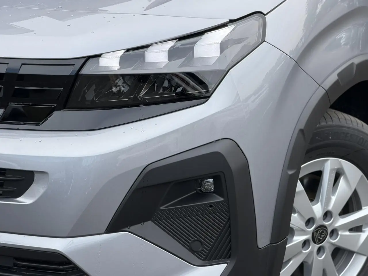 Gros plan sur l’avant droit gris acier du Peugeot Rifter 2026, mettant en valeur le phare LED et la jante alu.