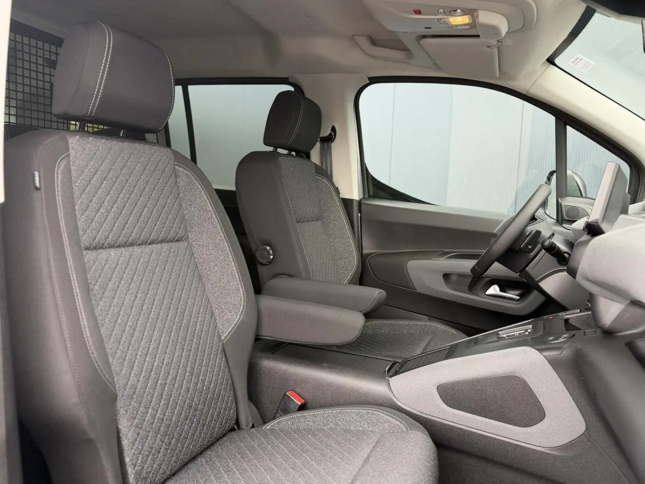 Vue intérieure côté droit du Peugeot Rifter 2026, sièges tissu gris avec accoudoirs et tablette tactile visible.