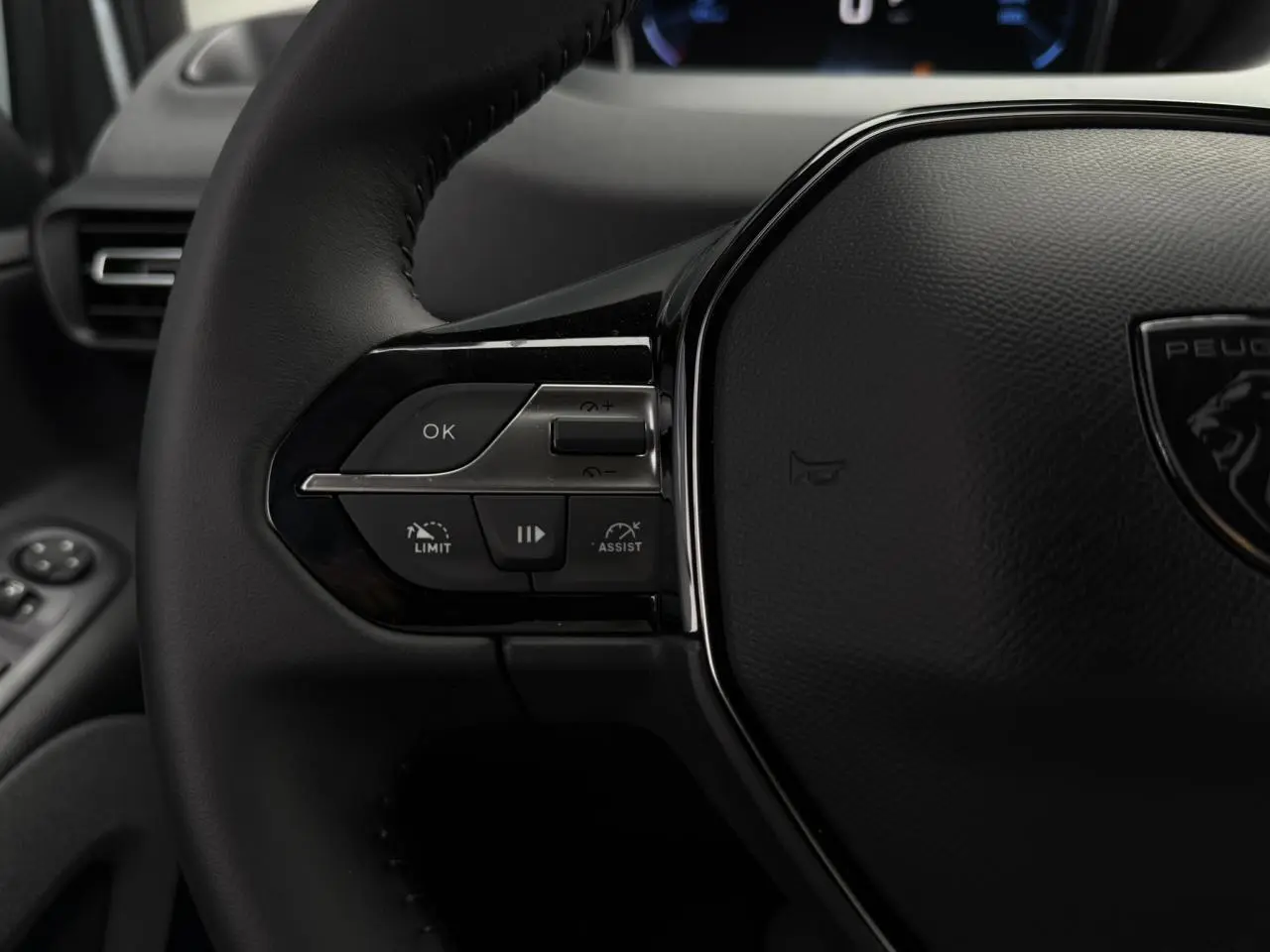 Gros plan sur le volant cuir multifonction du Peugeot Rifter 2026, avec commandes intégrées et logo lion central.