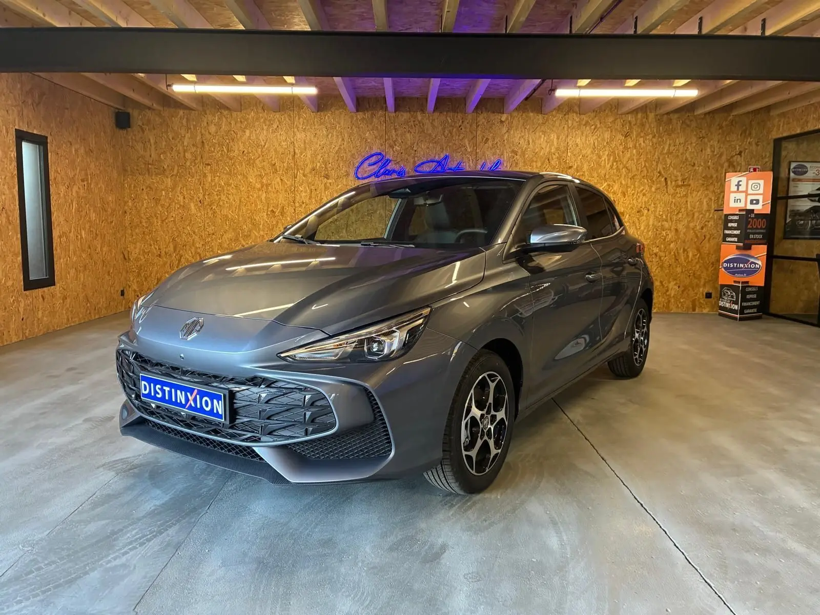 Vue 3/4 avant d’une MG3 gris métallisé 2026 en intérieur, avec calandre noire et jantes au design distinctif.