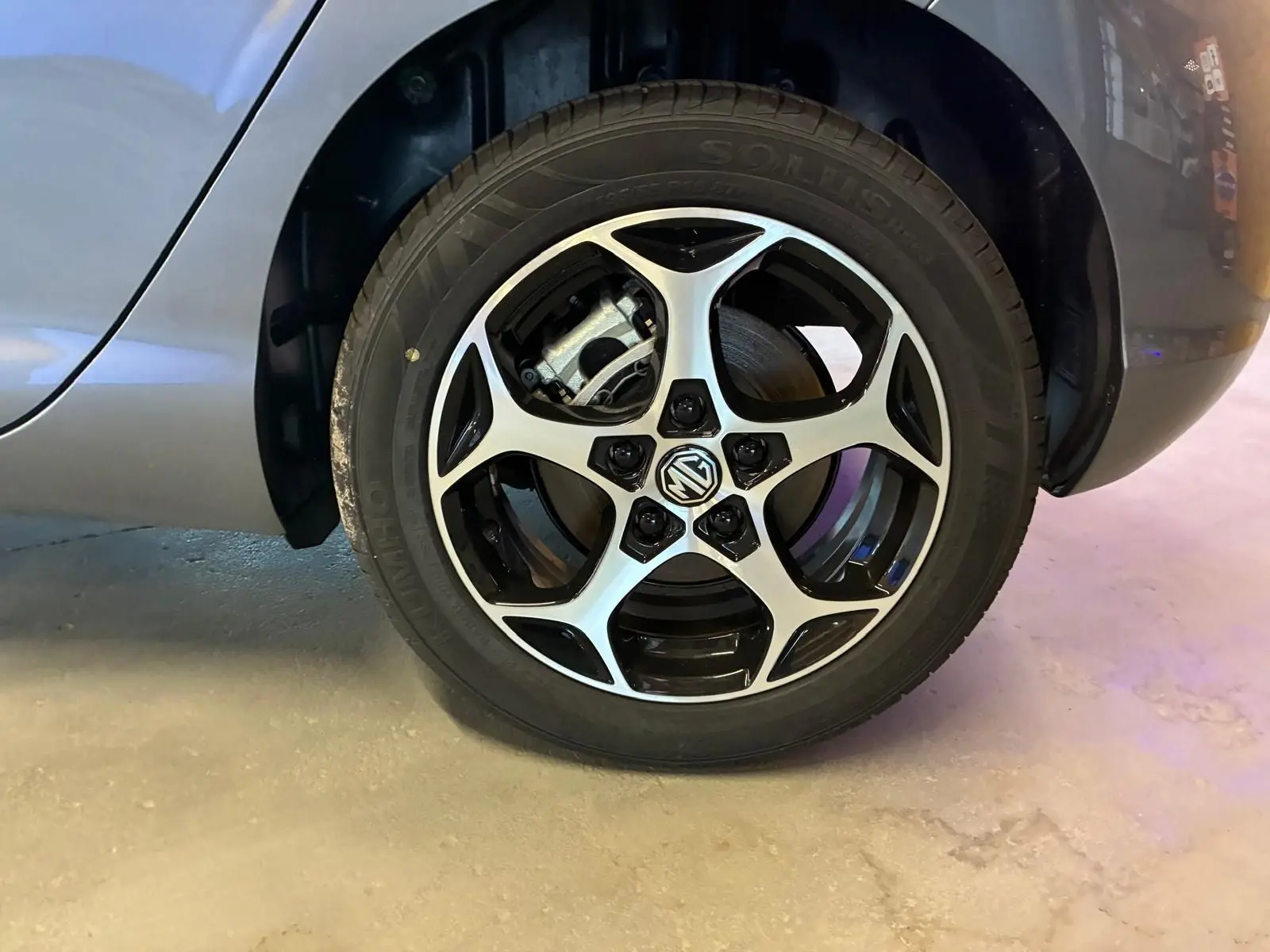 Gros plan sur la roue avant droite noire du MG3 1.5 HYBRID+ 195 LUXURY avec jante alliage bicolore et logo MG central.