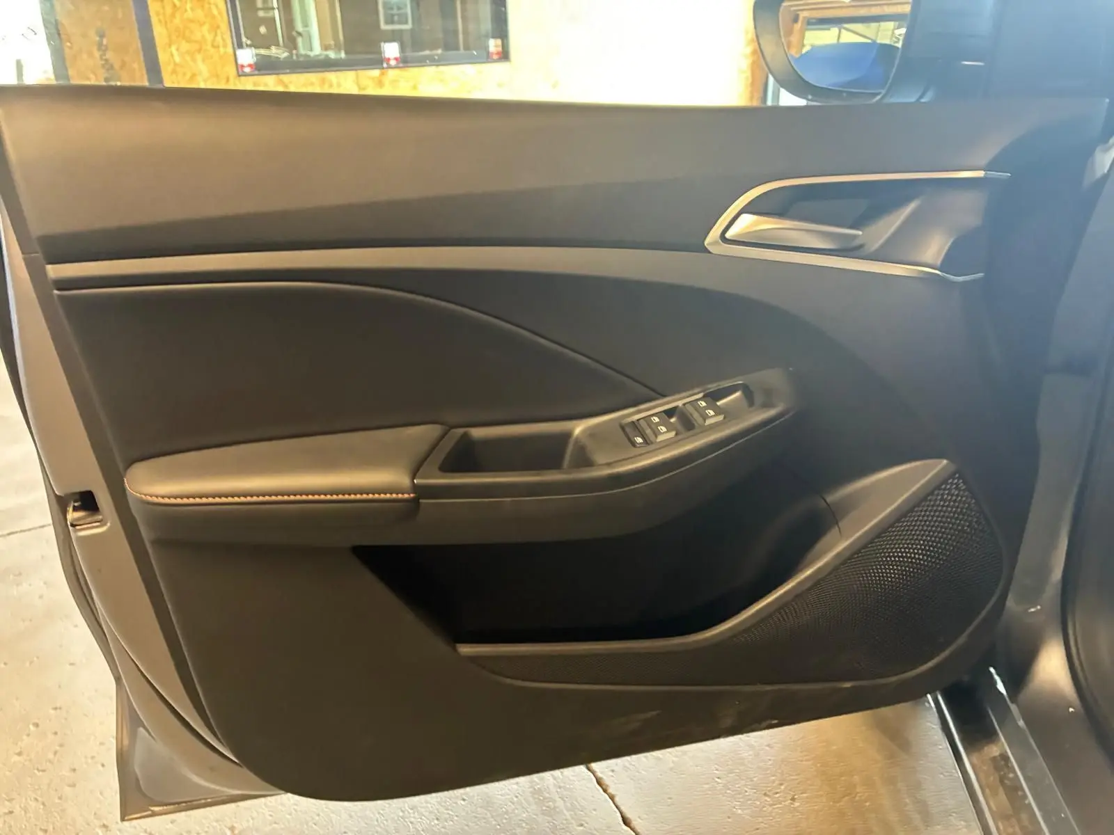 Vue intérieure de la porte avant gauche noire du MG3 1.5 HYBRID+ 195 LUXURY avec commandes de vitres et haut-parleur intégré.