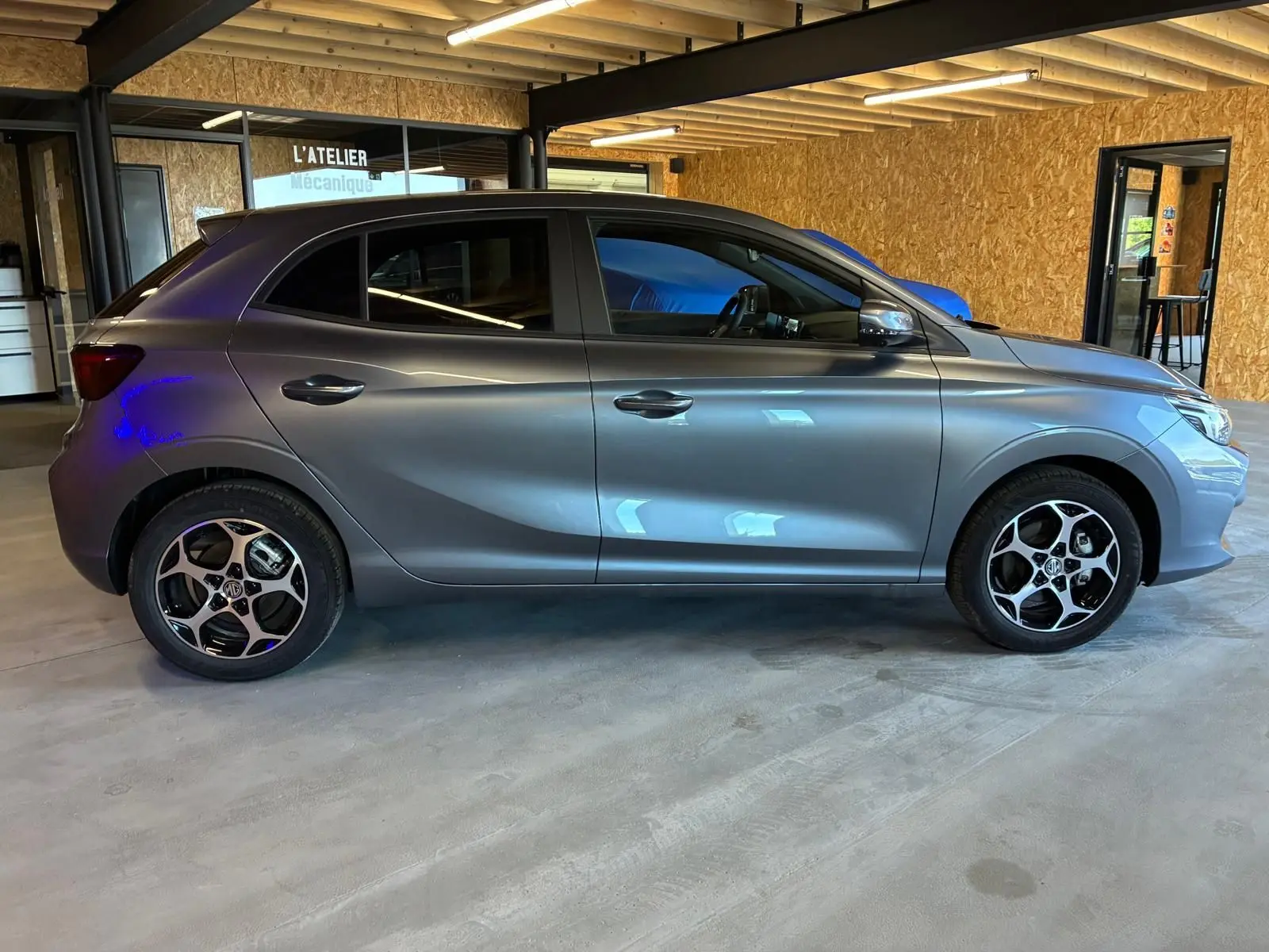 Vue de profil côté gauche d'une MG3 1.5 HYBRID+ 195 LUXURY gris métallisé avec jantes noires et argent.