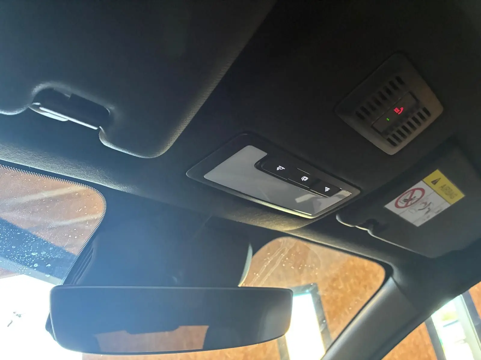 Vue intérieure du toit et du rétroviseur intérieur d'une MG3 1.5 HYBRID+ 195 LUXURY noire, avec commandes de plafonnier et pare-soleil visible.