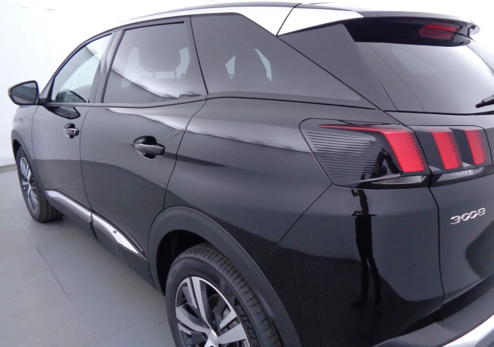 Vue 3/4 arrière gauche d'un Peugeot 3008 noir Perla Nera avec feux arrière à griffes rouges distinctifs.