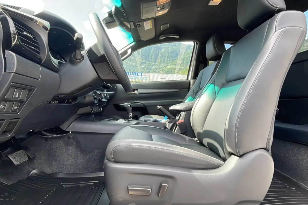 Intérieur du Toyota Hilux 2025 X-TRA D-4D 204 BVA Invincible, vue côté conducteur sur sièges cuir gris et tableau de bord.