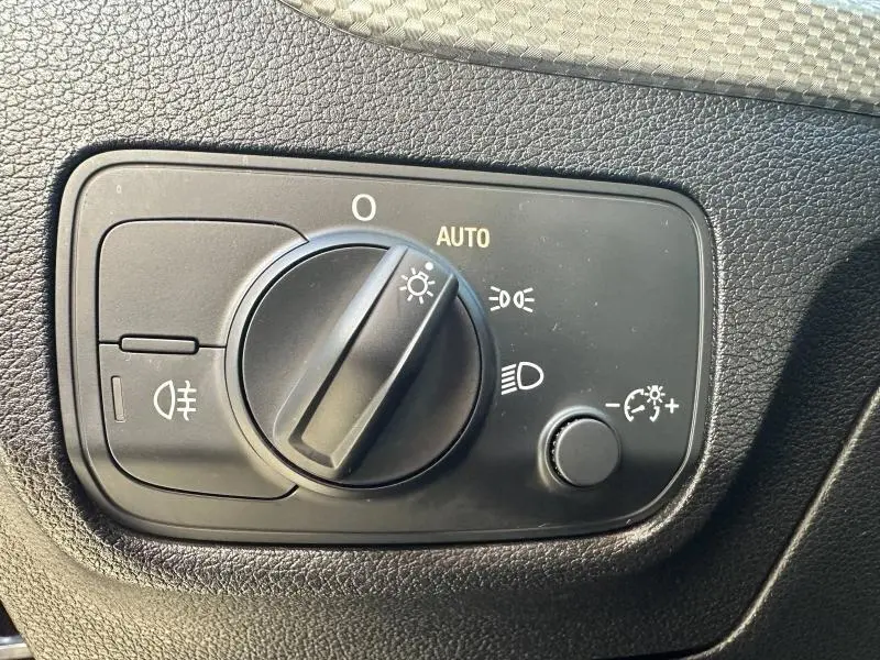 Gros plan sur le bouton de commande des phares de l'Audi Q2 35 TFSI S line 2023, intérieur noir texturé.