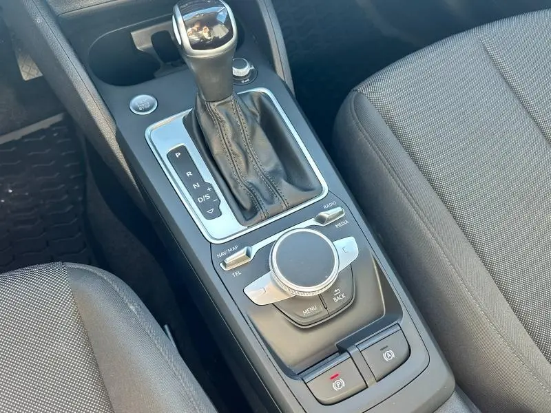Gros plan sur la console centrale noire de l'Audi Q2 35 TFSI S line 2023 avec levier de vitesses automatique et commandes multimédia.