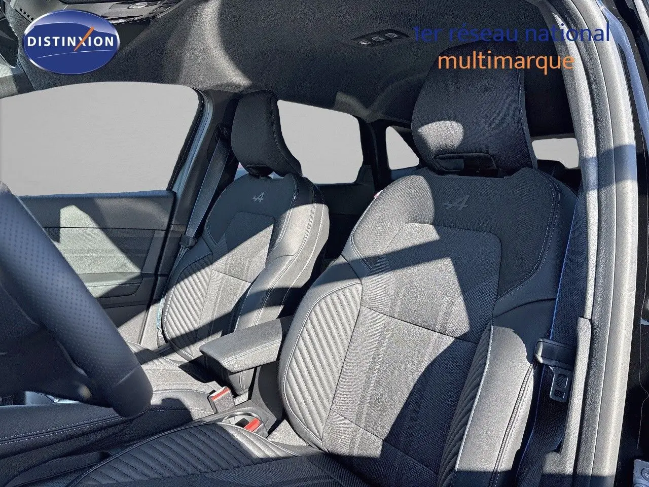 Vue intérieure côté conducteur montrant les sièges avant noirs en tissu et cuir avec logo Alpine brodé sur Renault Symbioz 2025.