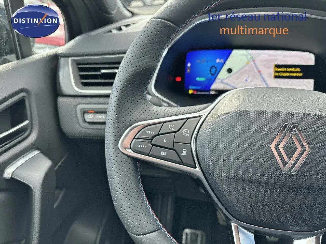 Vue rapprochée du volant noir perforé avec commandes intégrées et tableau de bord numérique du Renault Symbioz hybride.