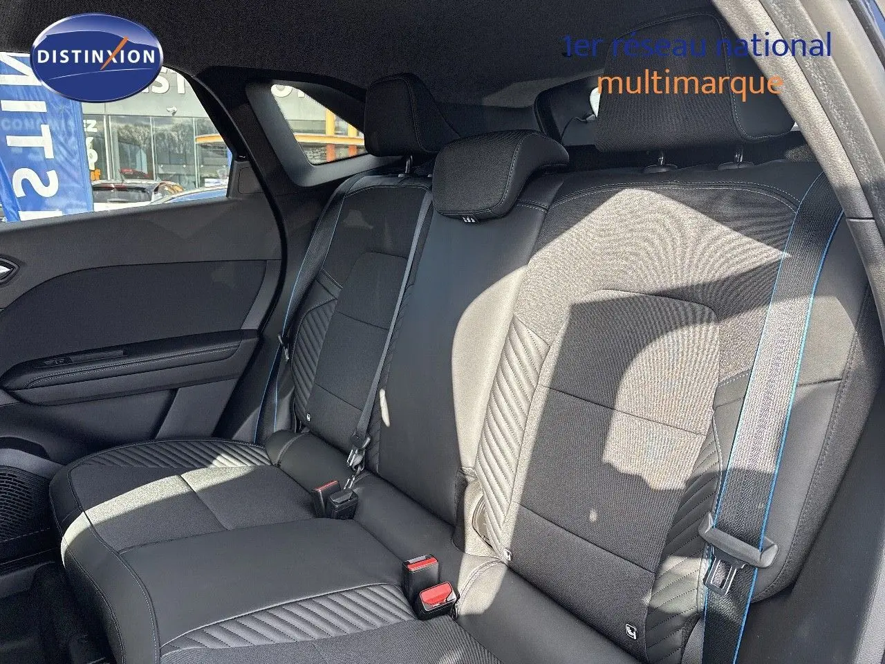 Vue latérale des sièges arrière noirs en cuir et tissu avec surpiqûres bleues du Renault Symbioz hybride 2025.