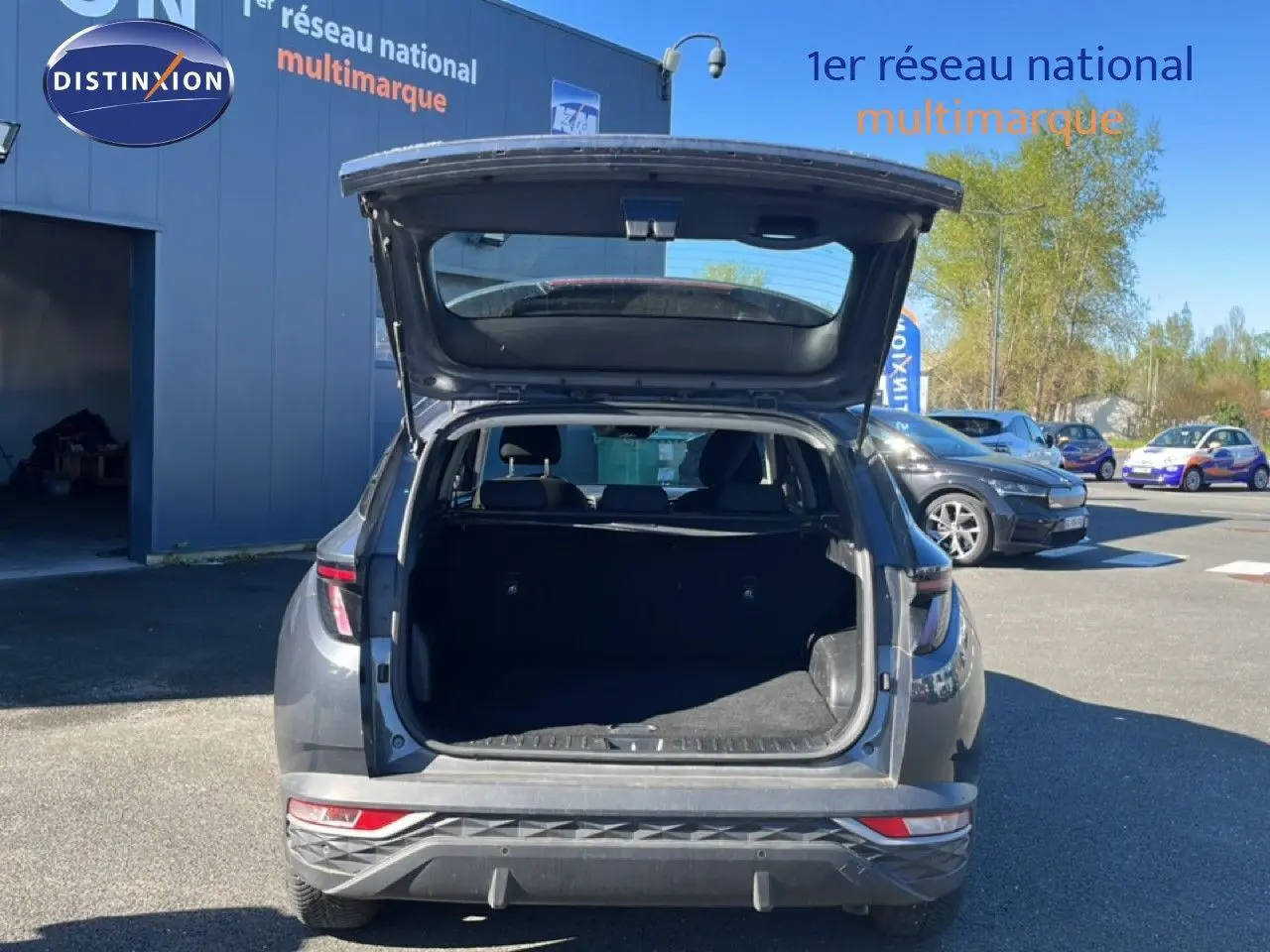 Vue arrière d’un Hyundai Tucson gris foncé métal 2021 avec coffre ouvert, dévoilant l’espace de chargement vide.