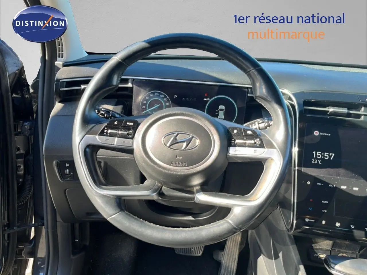 Vue intérieure centrée sur le volant du Hyundai Tucson gris foncé, avec tableau de bord numérique et écran tactile visible.