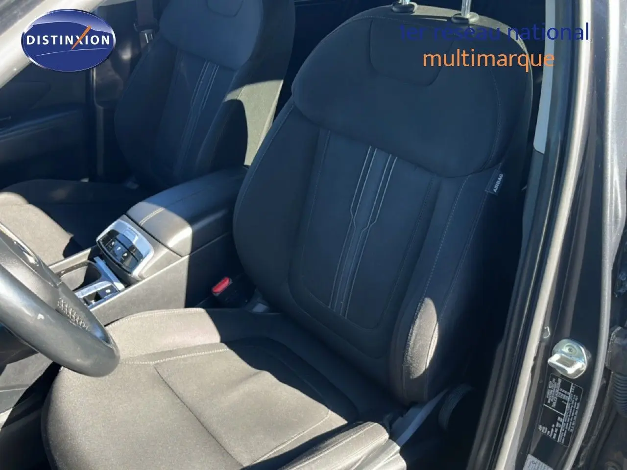 Vue intérieure côté conducteur du Hyundai Tucson gris foncé métal, mettant en valeur le siège avant en tissu noir et la console centrale.