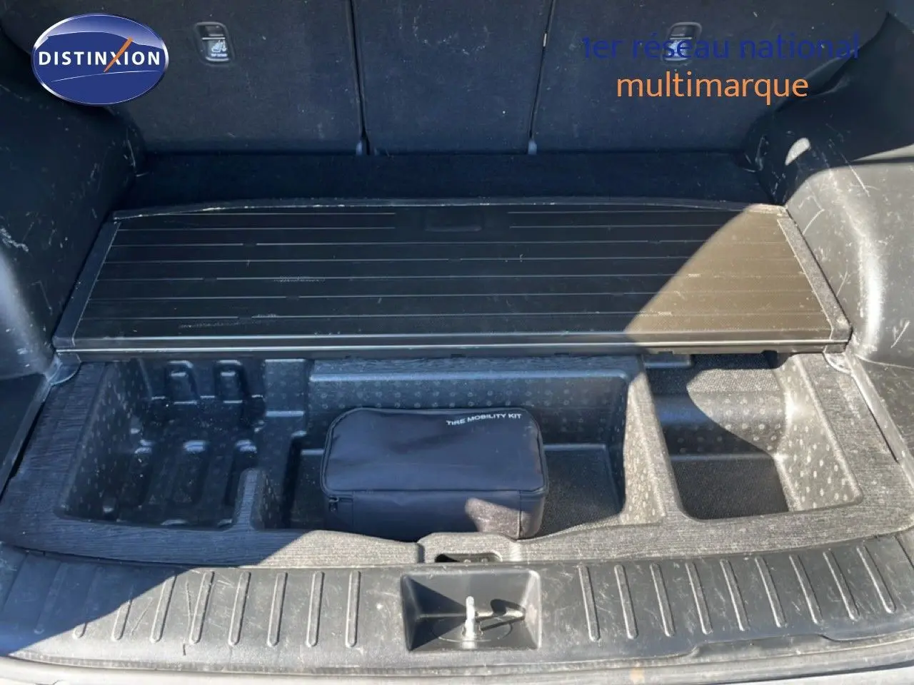 Coffre ouvert du Hyundai Tucson gris foncé, montrant le rangement sous plancher avec trousse de mobilité.