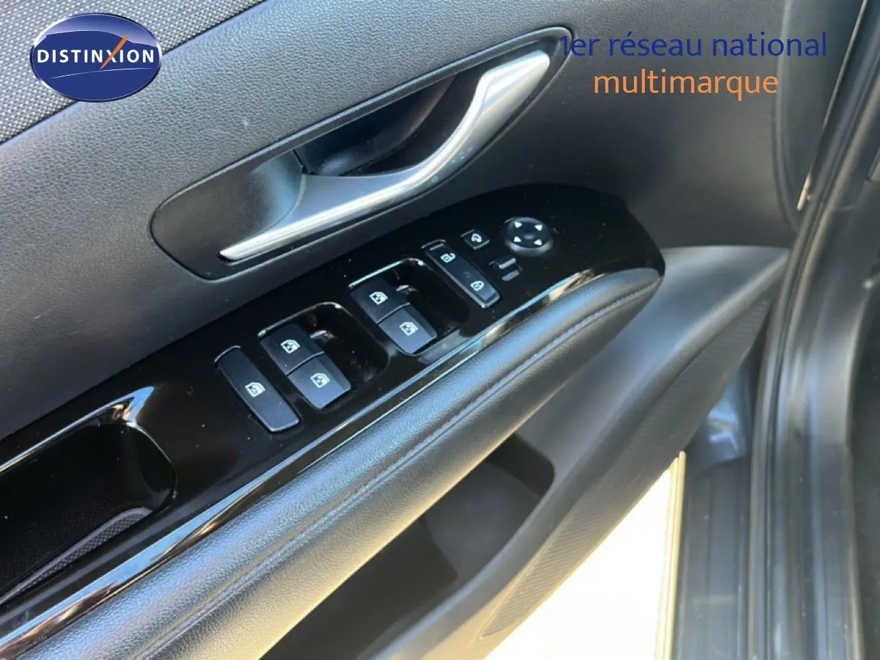 Gros plan sur la porte côté conducteur du Hyundai Tucson gris foncé, montrant les commandes des vitres et la poignée intérieure.