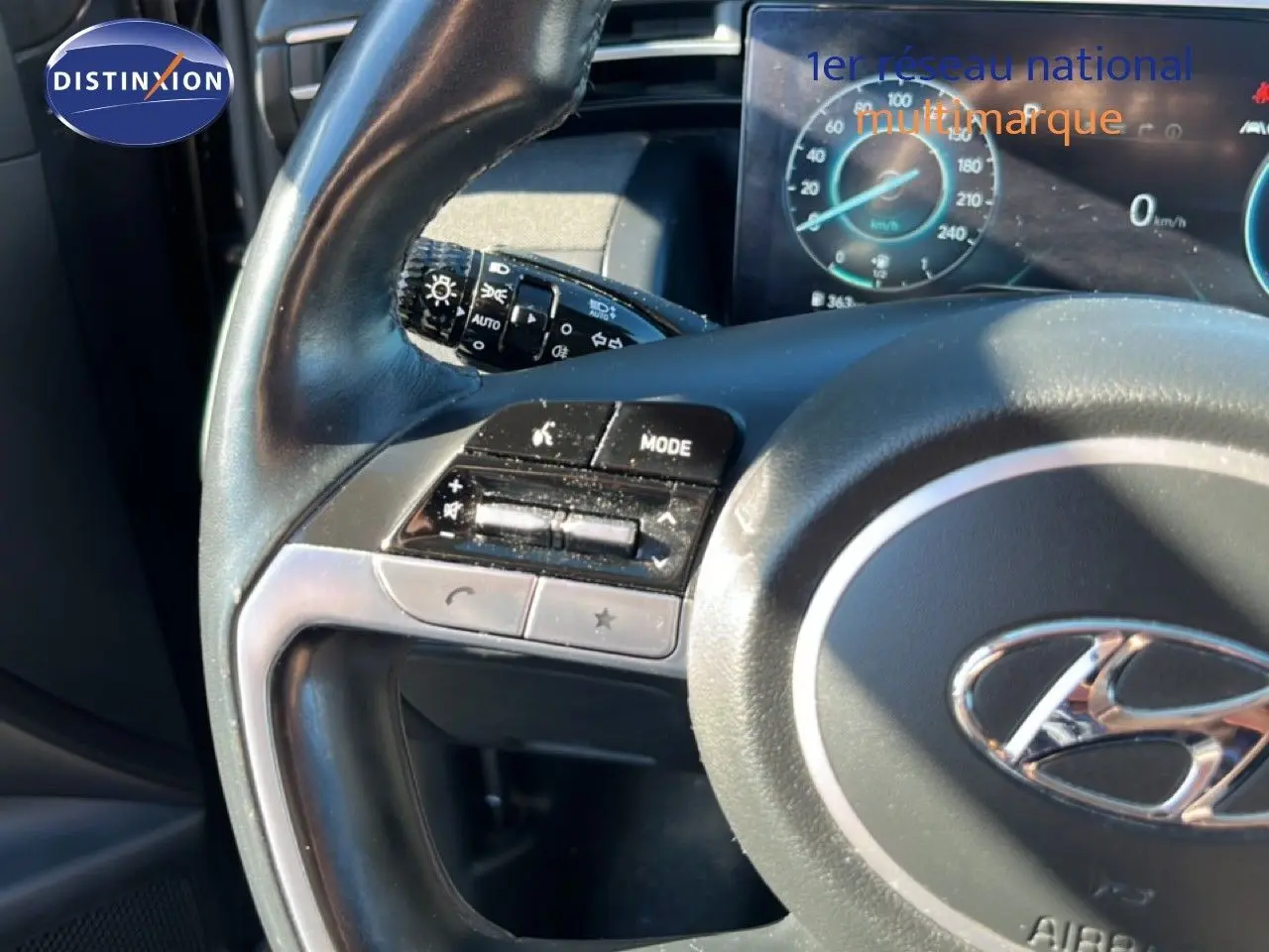 Gros plan sur le volant et le tableau de bord du Hyundai Tucson gris foncé 2021, avec commandes intégrées et affichage digital.