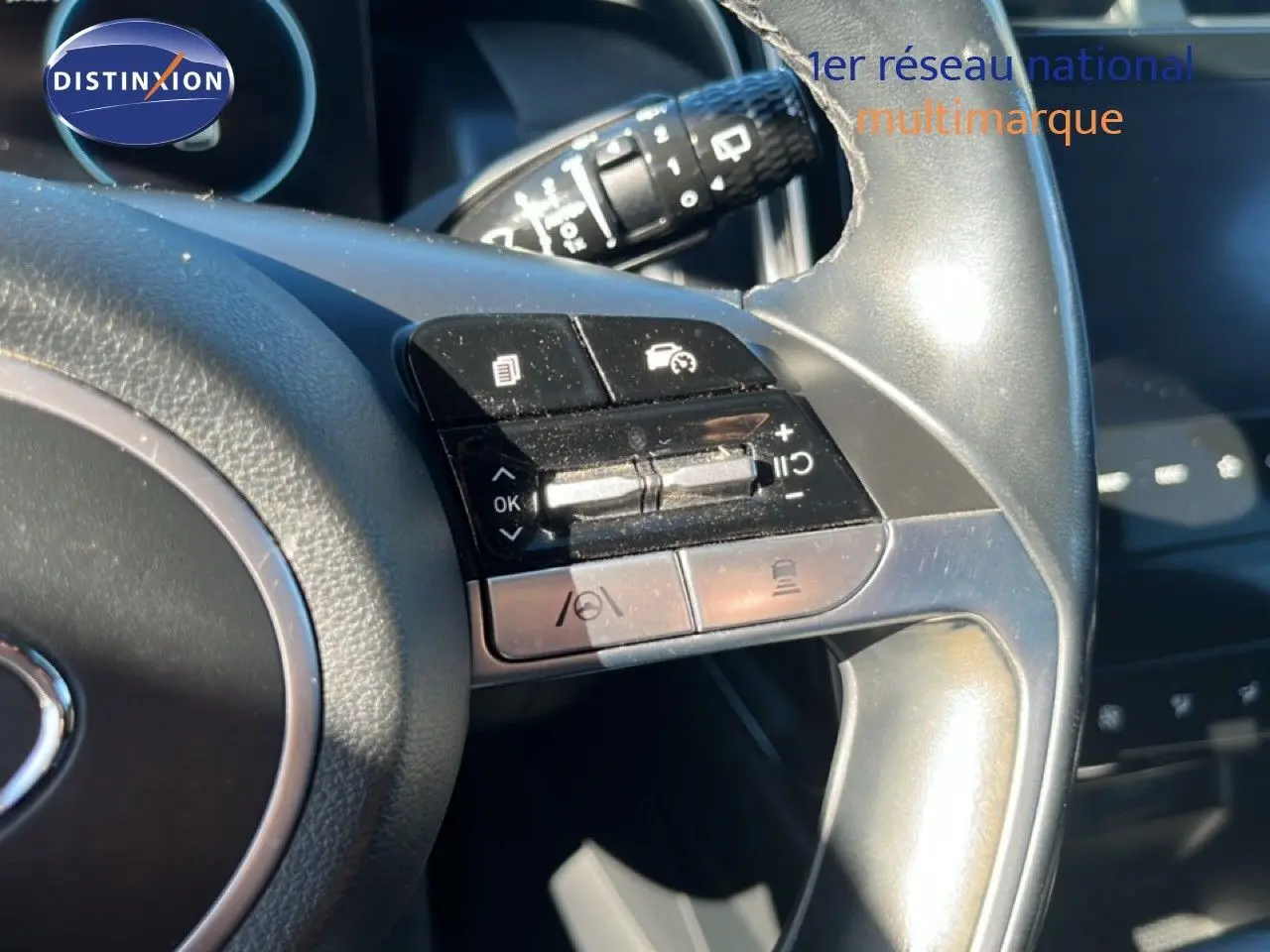 Gros plan sur les commandes au volant gris foncé du Hyundai Tucson 2021, mettant en valeur les boutons multifonctions.