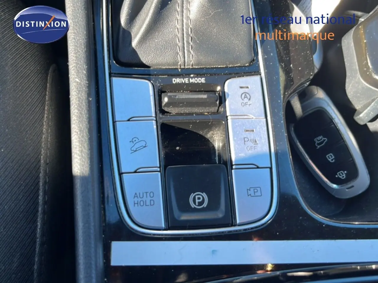 Gros plan sur la console centrale du Hyundai Tucson gris foncé, montrant les commandes de conduite et la clé.