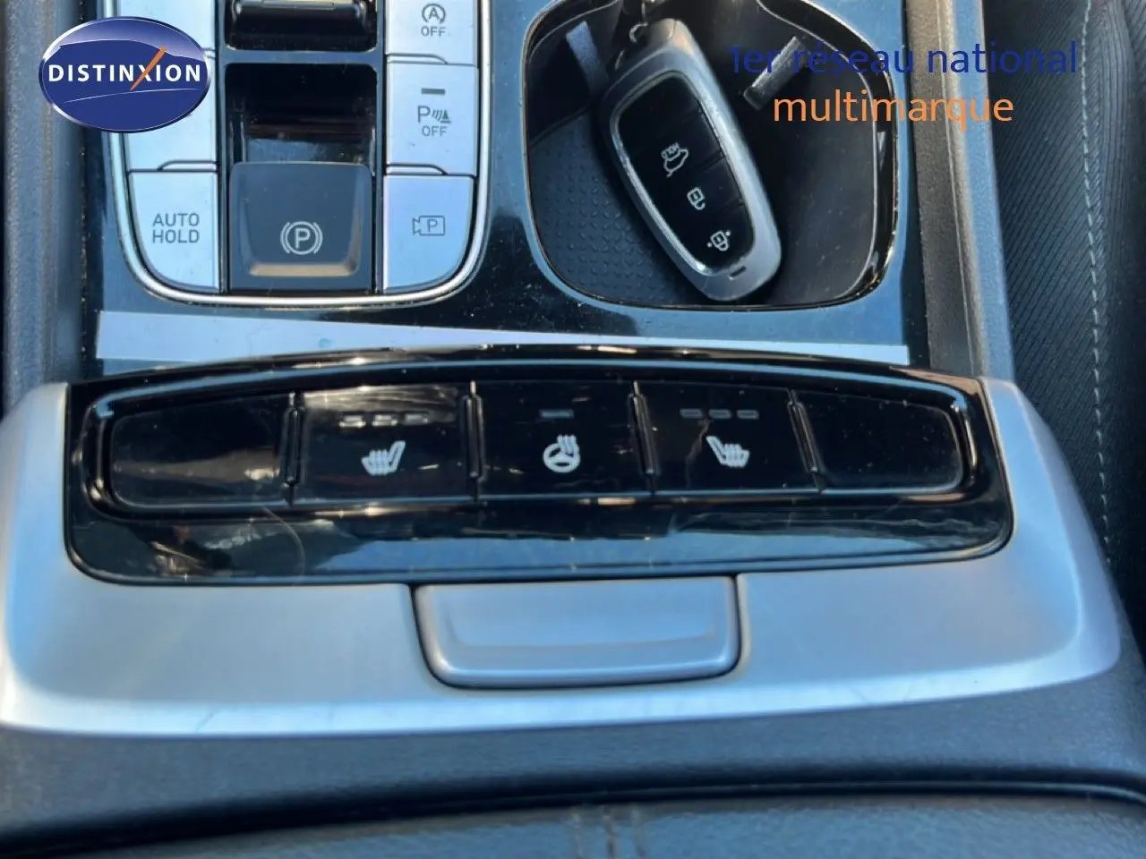 Vue rapprochée de la console centrale du Hyundai Tucson 2021, boutons de sièges chauffants et clé noire visible.