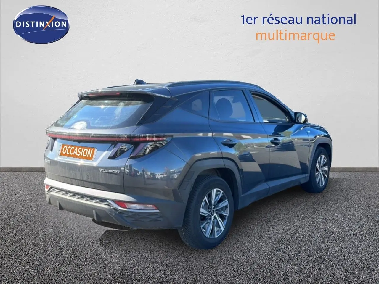Vue 3/4 arrière droite d'un Hyundai Tucson gris foncé métal 2021 avec feux arrière étirés et jantes alliage.