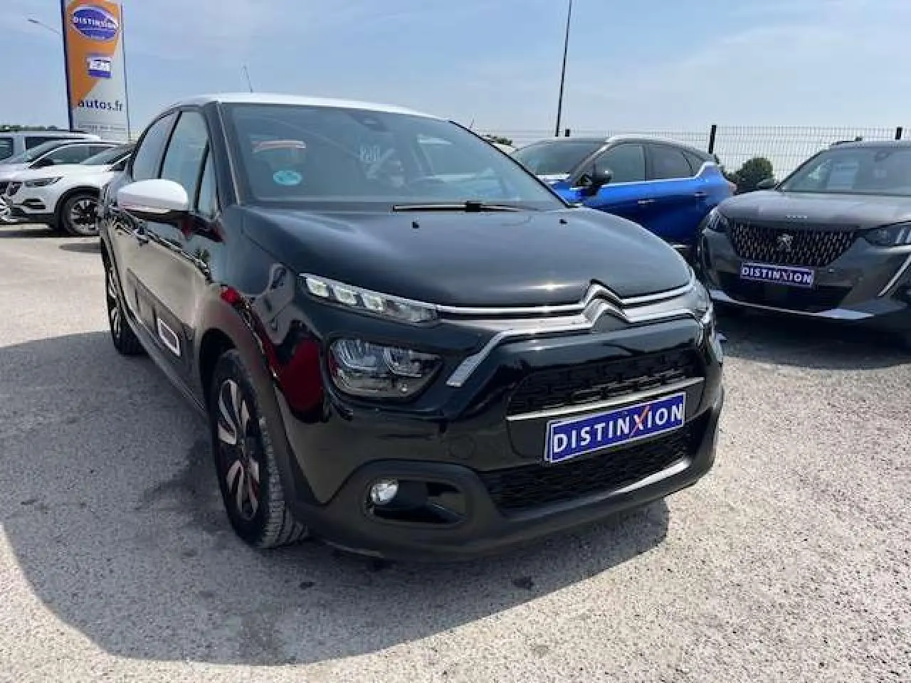 Citroën C3 2023 noir avec toit blanc en 3/4 avant droit, jantes alliage et rétroviseurs blancs visibles.