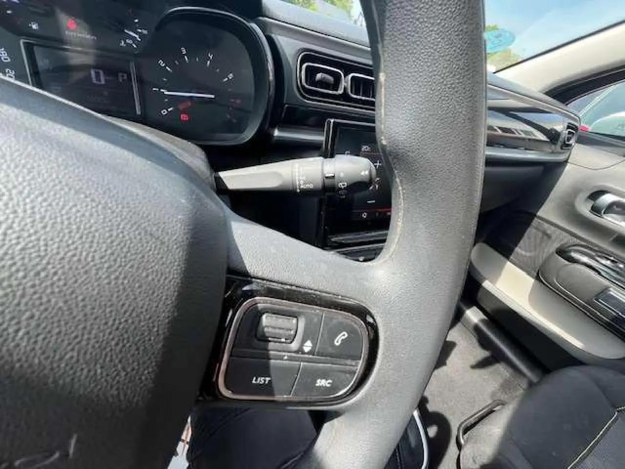 Vue rapprochée du volant côté gauche de la Citroën C3 2023 noire, avec commandes audio intégrées et tableau de bord visible.