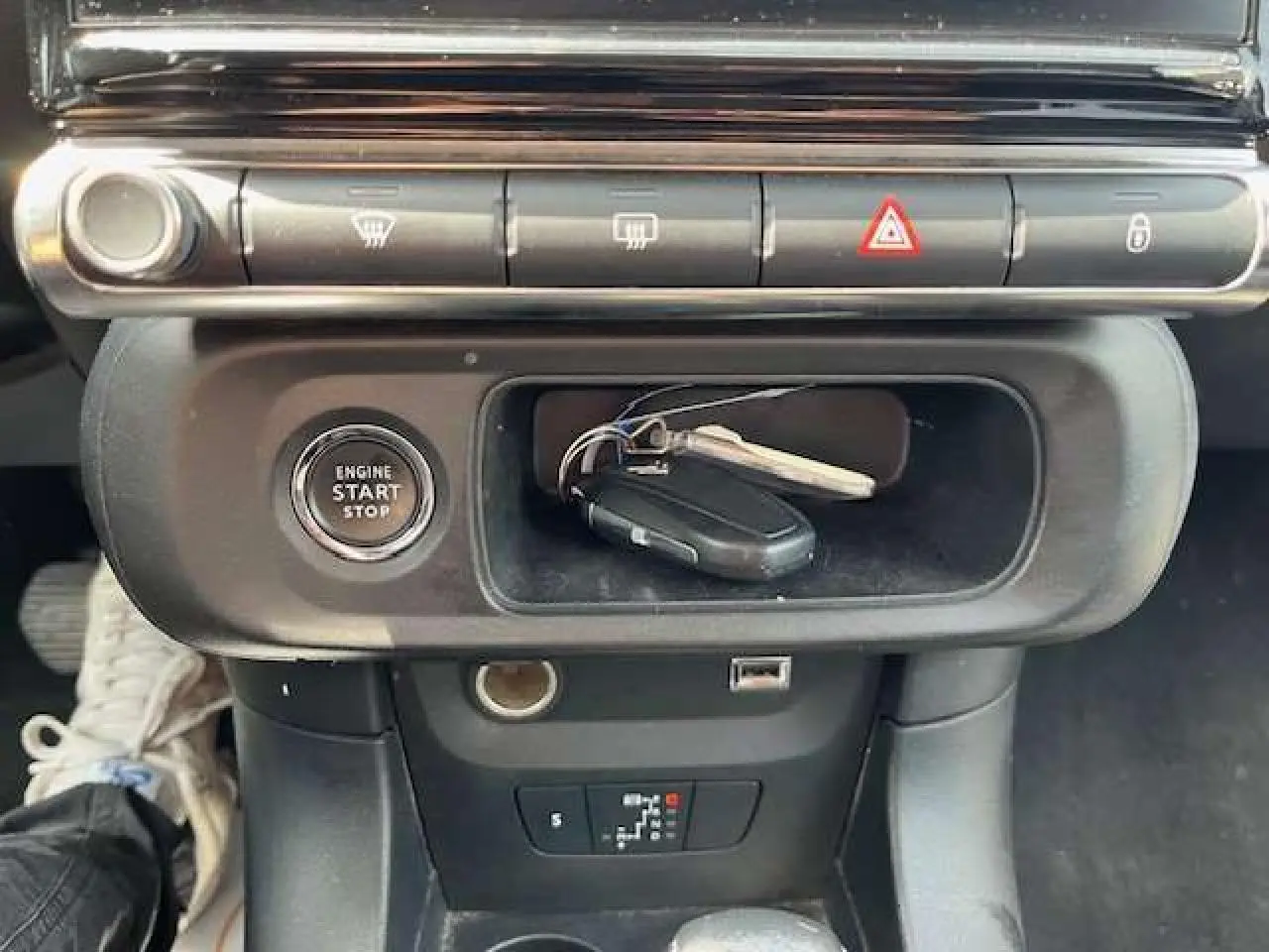 Gros plan intérieur sur la console centrale noire de la Citroën C3 2023 avec bouton start/stop et clé posée.