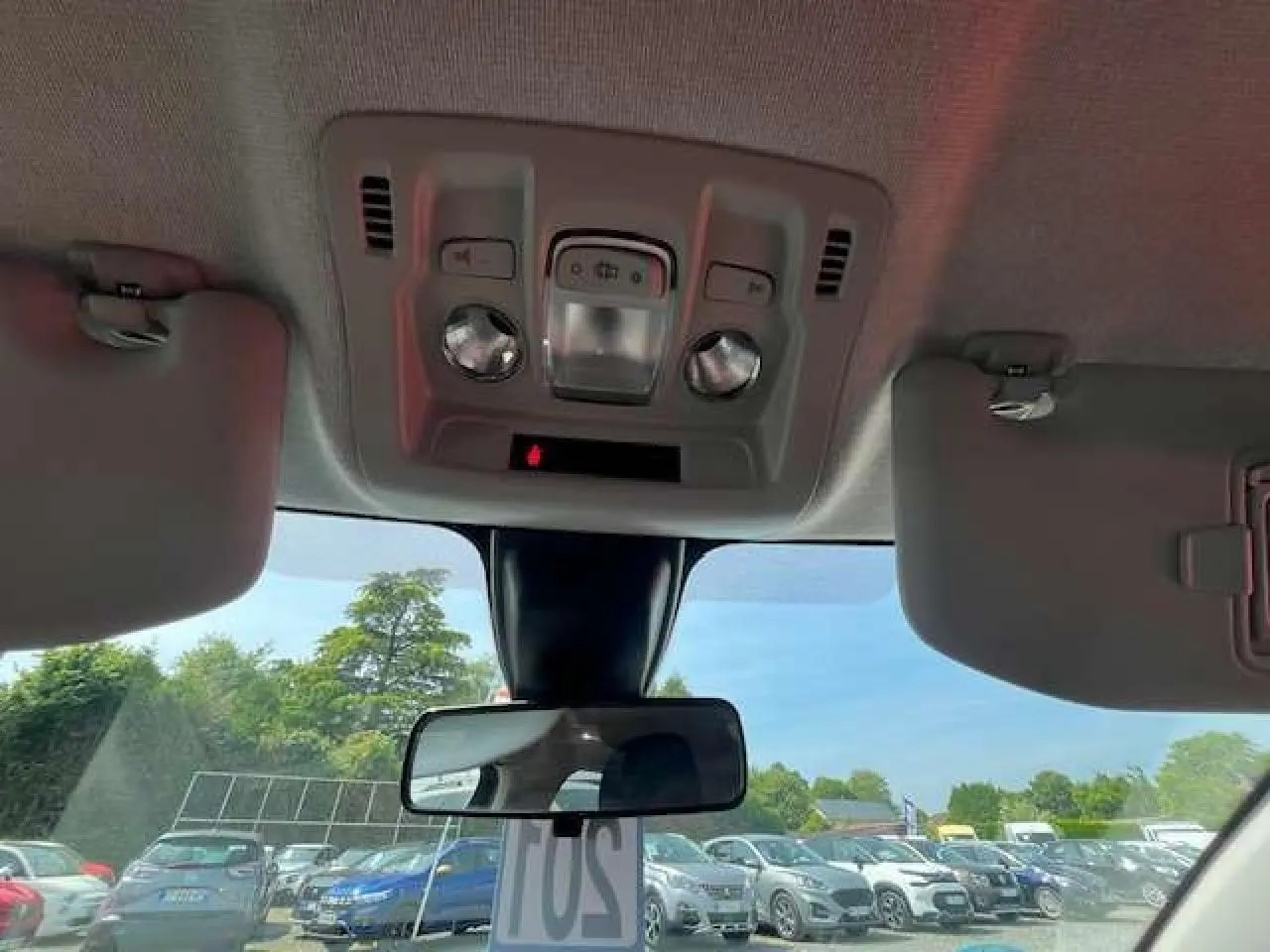 Vue intérieure du toit et rétroviseur central d'une Citroën C3 2023, avec pare-soleil baissé et ciel visible à travers le pare-brise.