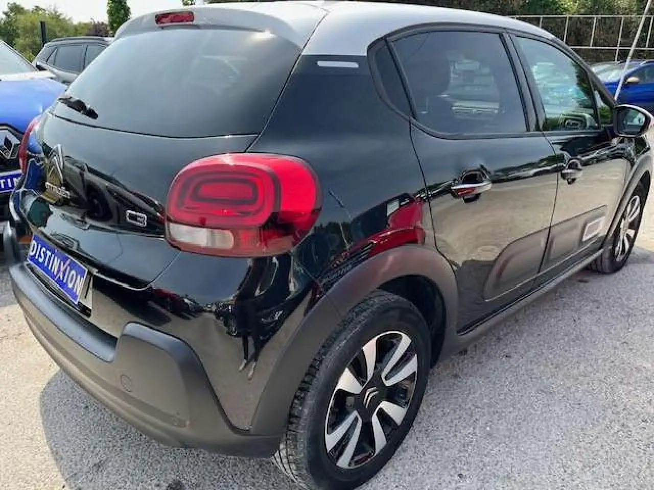 Vue 3/4 arrière droite d'une Citroën C3 noire avec toit blanc, jantes alliage diamantées et vitres surteintées.