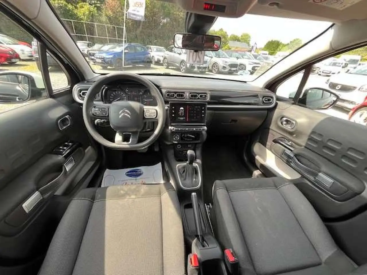 Vue intérieure avant de la Citroën C3 2023, tableau de bord noir avec volant multifonction et console centrale avec écran tactile.