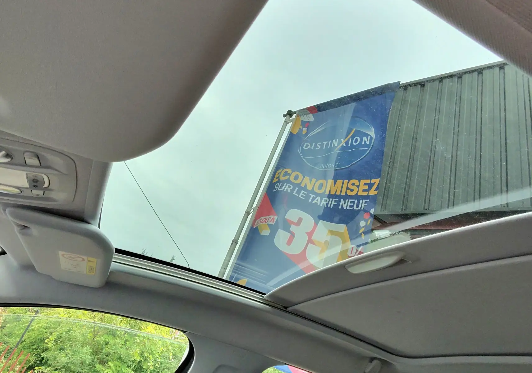 Vue intérieure du toit ouvrant panoramique et des sièges avant noirs d'une Peugeot 208 gris foncé, version Allure 2017.