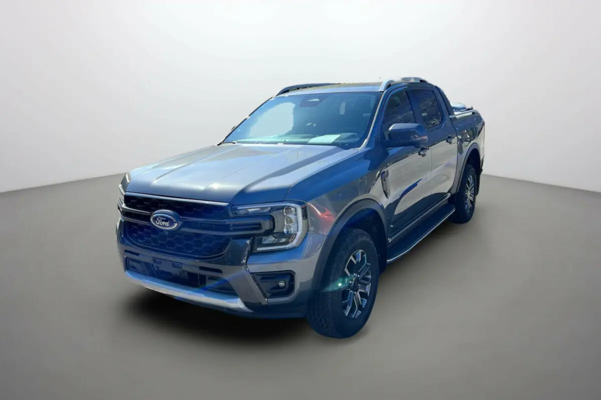 Ford Ranger Wildtrak gris carbone vu en 3/4 avant droit avec barres de toit et jantes alu 18 pouces.