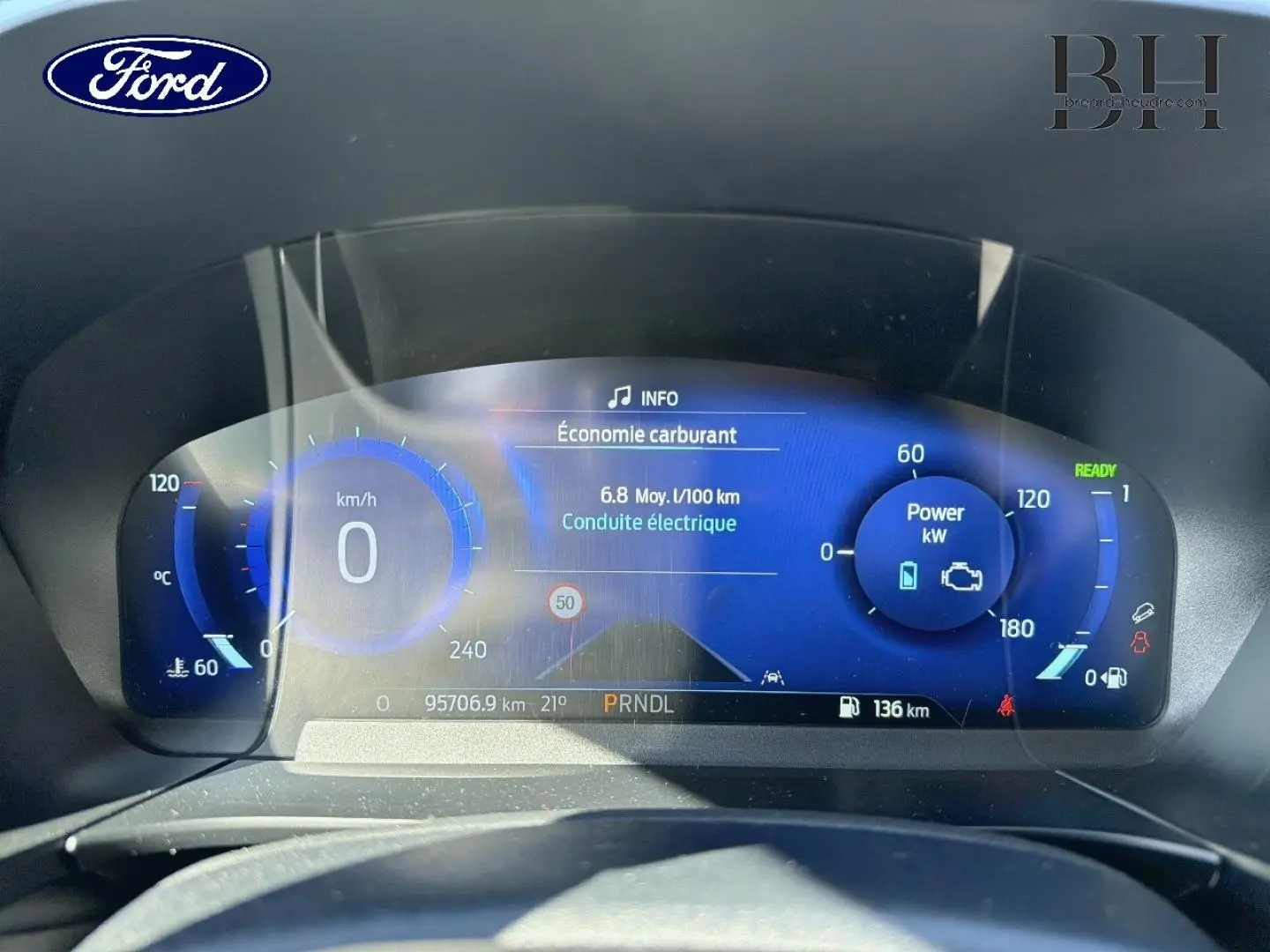 Vue rapprochée du tableau de bord numérique bleu du Ford Kuga 2021 affichant consommation et puissance électrique.
