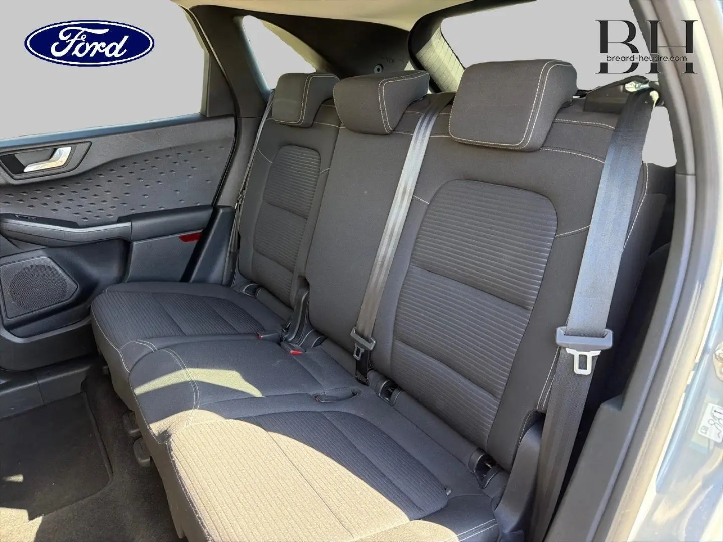 Vue latérale droite de la banquette arrière noire du Ford Kuga 2021, avec ceintures de sécurité et porte gris métallisé ouvert.