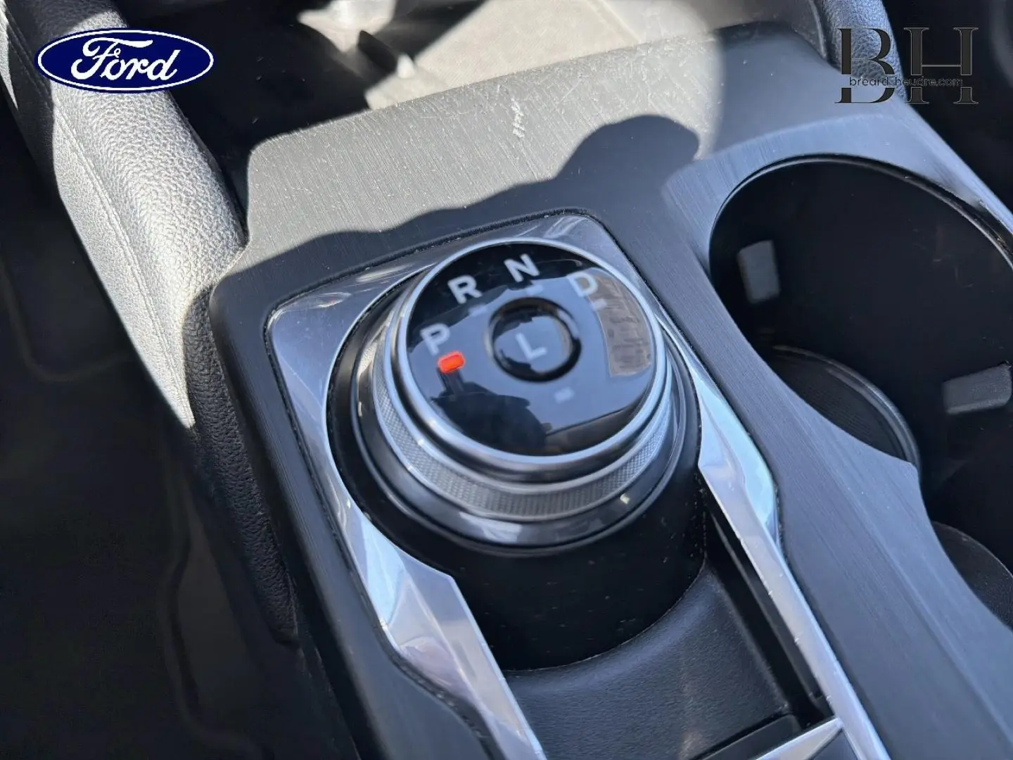 Gros plan sur la molette de sélection de vitesses du Ford Kuga 2.5 Hybride, finition Titanium, avec console noire et détails chromés.