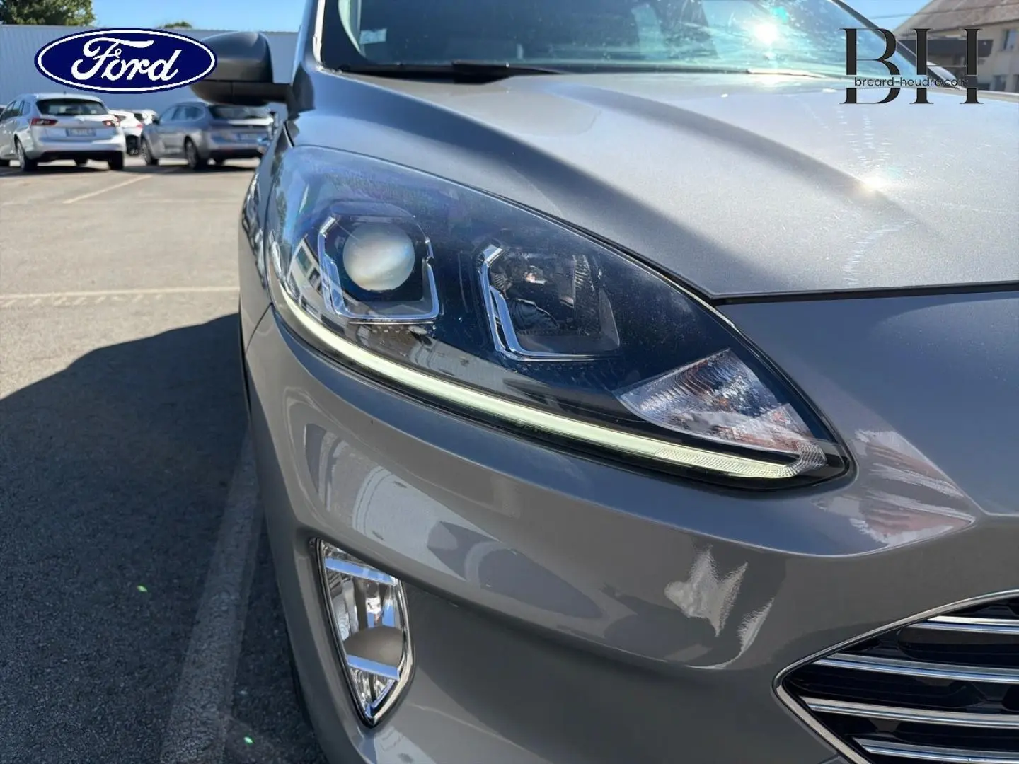 Gros plan sur l'avant droit du Ford Kuga gris Solar métallisé, mettant en valeur le phare LED et la calandre chromée.