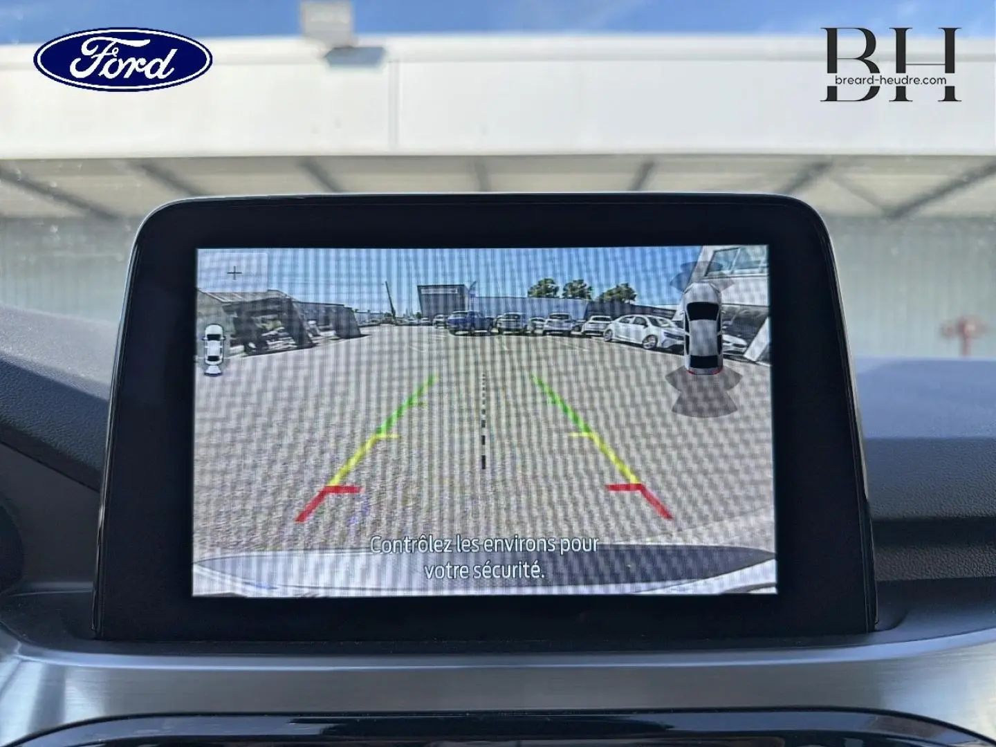 Écran tactile intérieur montrant la caméra de recul avec lignes de guidage colorées sur un Ford Kuga gris Solar.