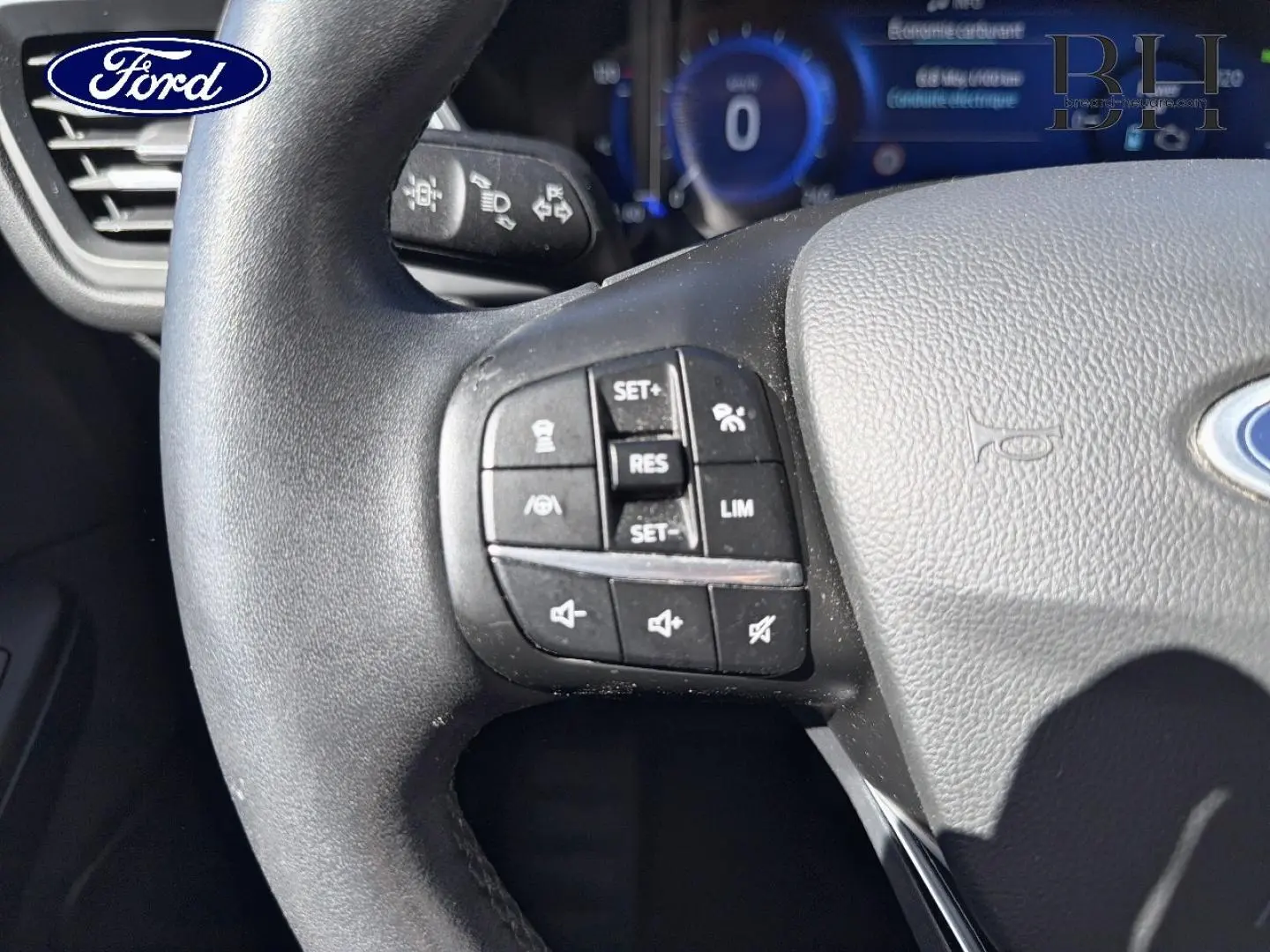 Gros plan sur le volant cuir multifonction noir du Ford Kuga 2021, avec commandes de régulateur de vitesse et audio.