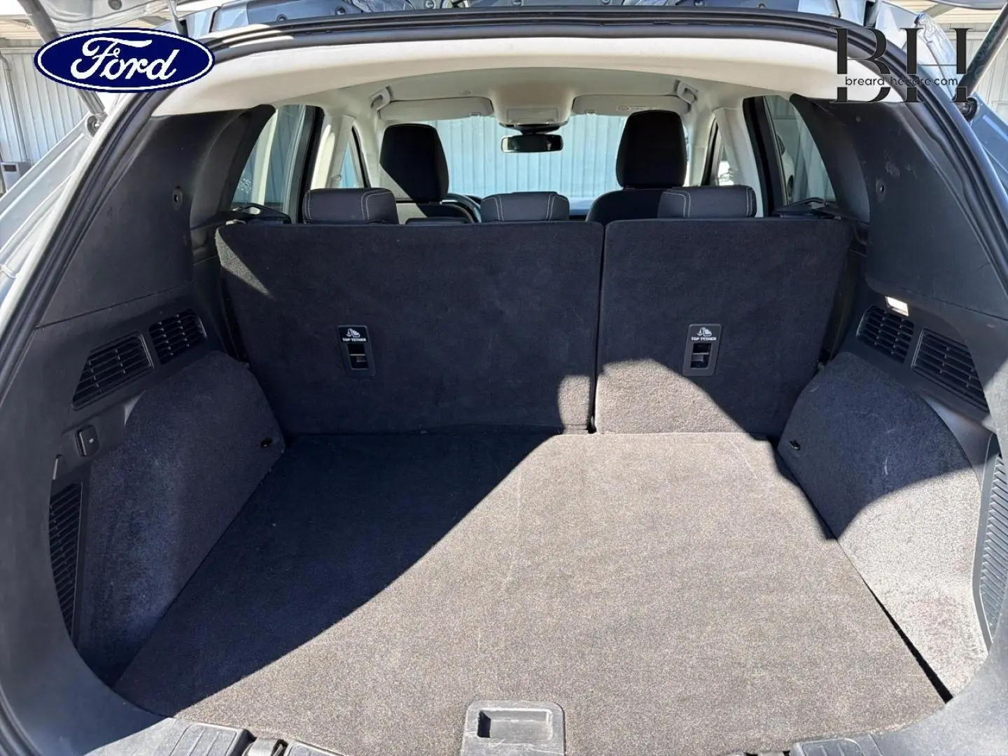 Coffre spacieux du Ford Kuga 2021, vue de l'arrière avec banquette arrière noire en position relevée.
