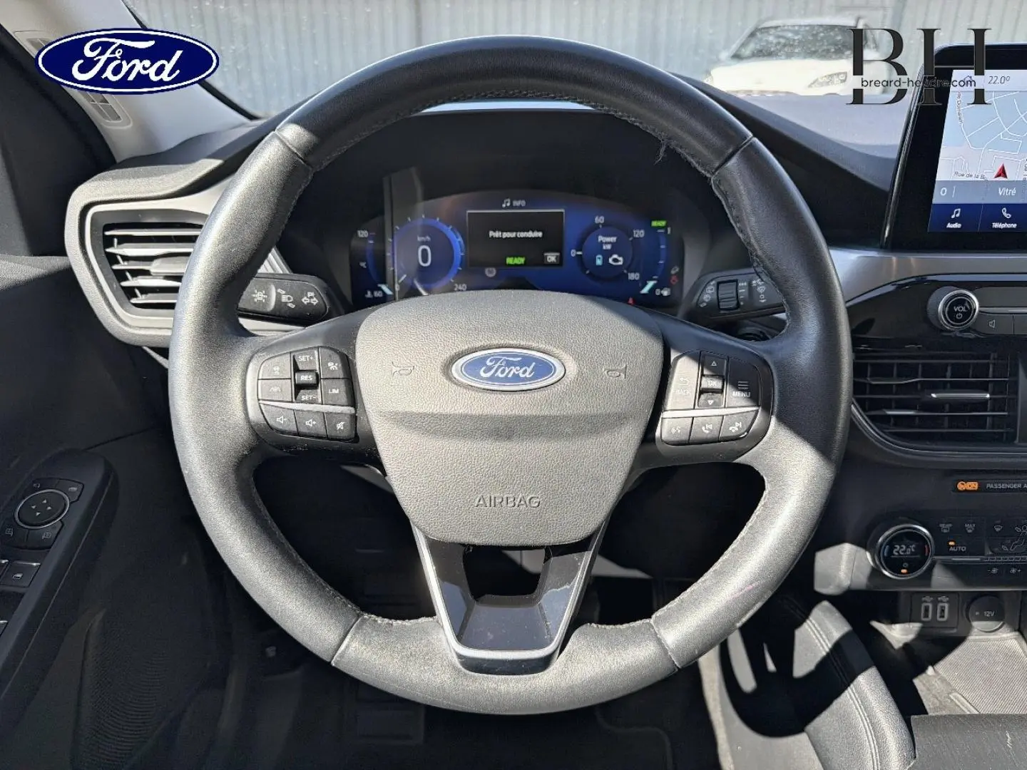 Vue intérieure centrée sur le volant cuir multifonction noir du Ford Kuga 2021 avec tableau de bord digital et écran tactile.