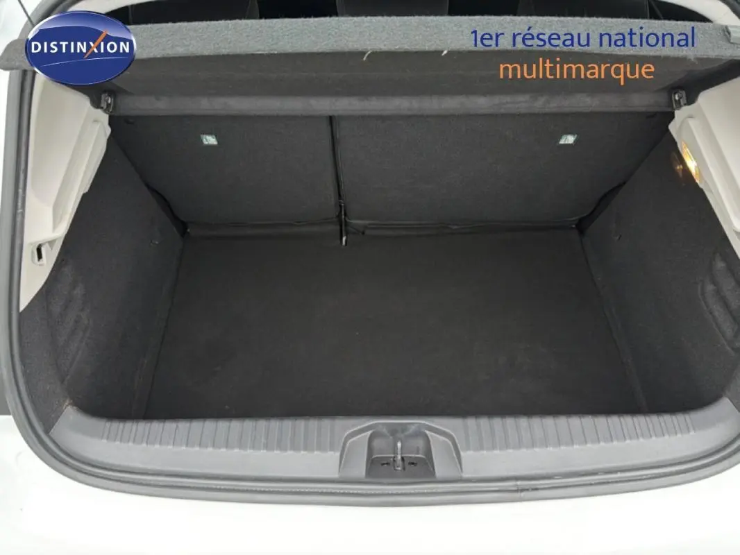 Coffre ouvert vu de l'arrière d'une Renault Clio blanche 2020, intérieur noir et espace de rangement vide.