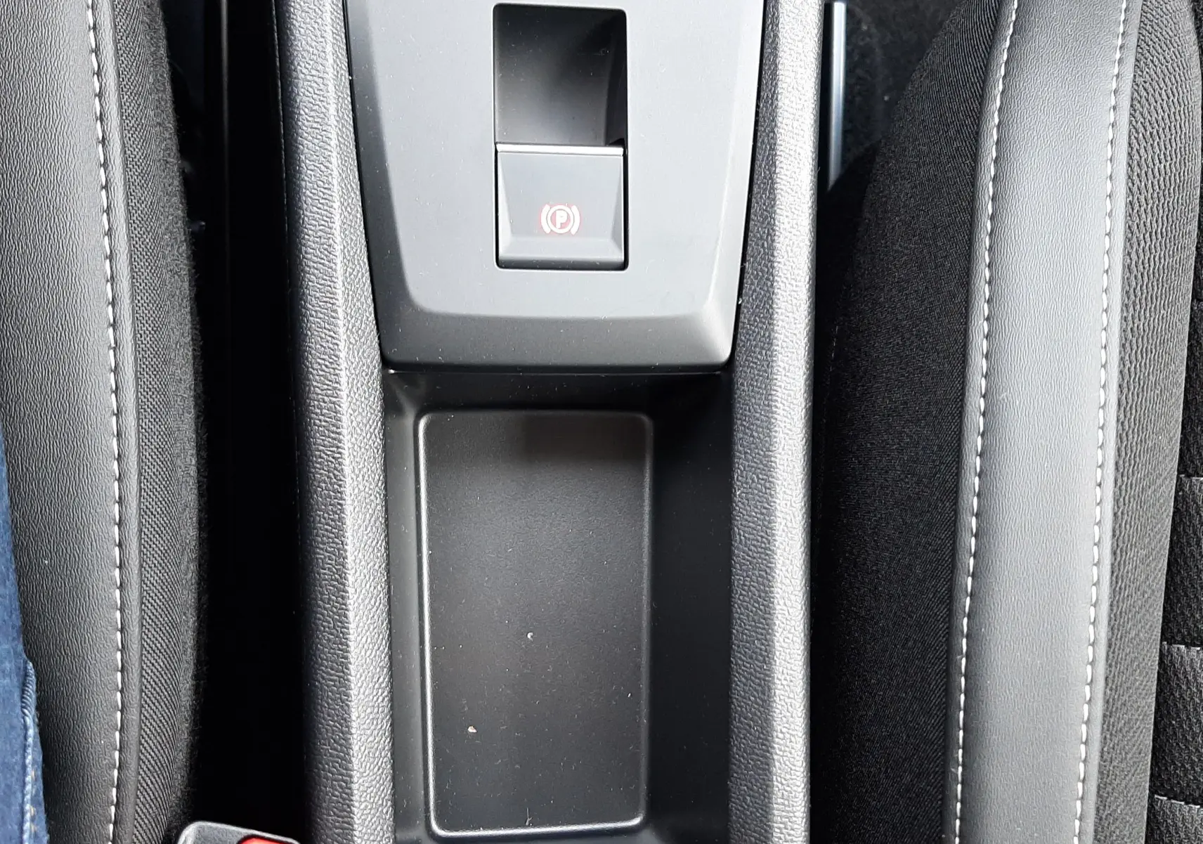 Vue plongeante sur la console centrale noire du Citroën C3 Aircross 2026, avec frein à main électronique et rangement vide.