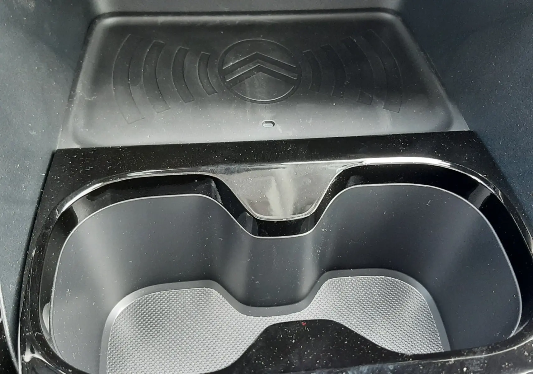 Gros plan sur le porte-gobelets noir brillant et la zone de recharge sans fil avec logo Citroën dans une Citroën C3 Aircross 2026.