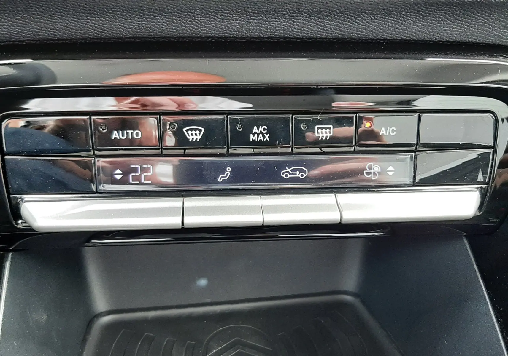 Gros plan sur la commande de climatisation digitale et le support de charge sans fil avec logo Citroën, intérieur noir.