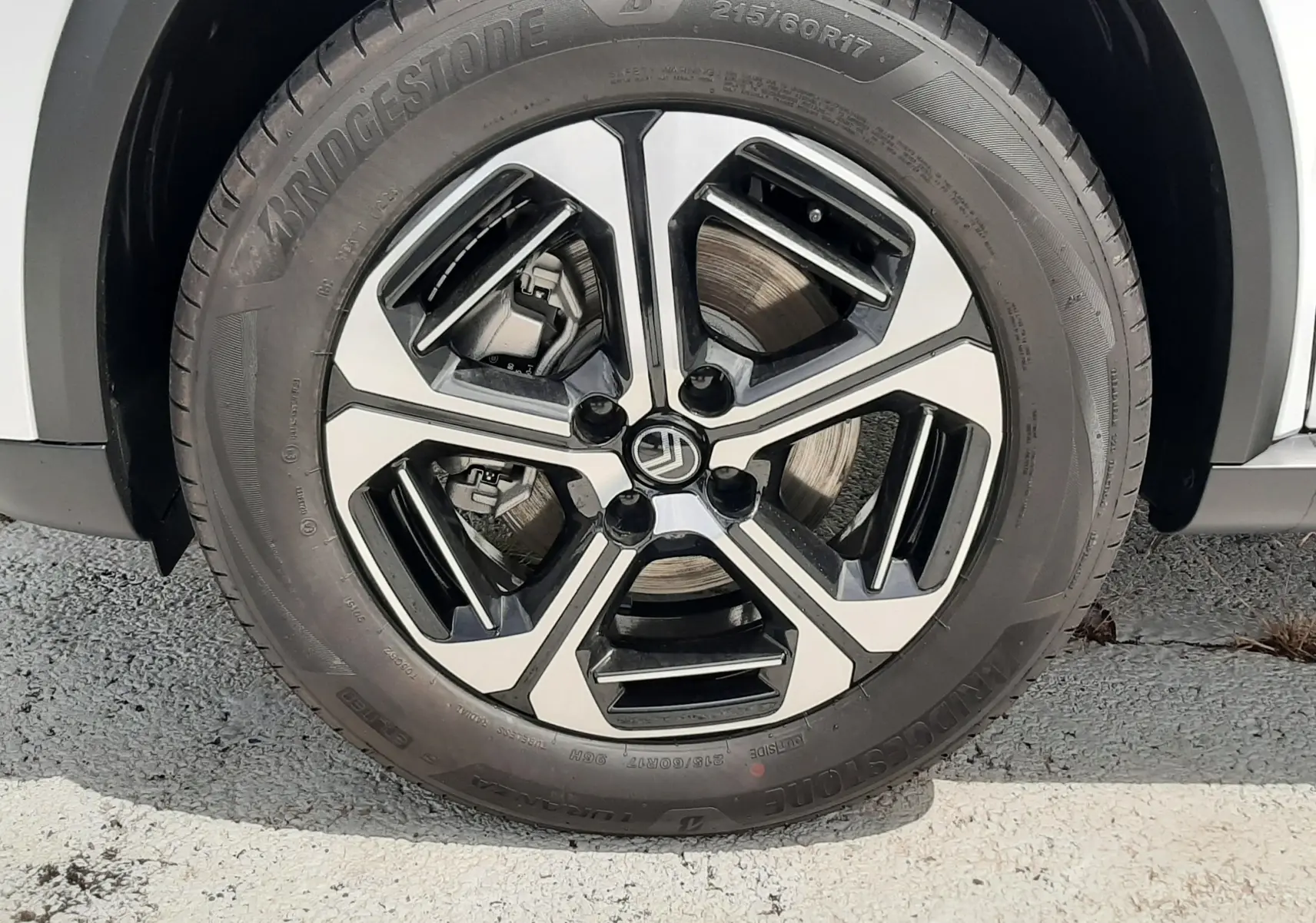 Gros plan sur la roue avant gauche du Citroën C3 Aircross blanc banquise avec jante alliage bicolore et pneu Bridgestone.