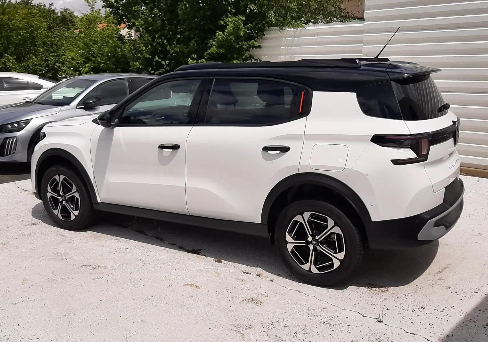 Vue 3/4 arrière côté droit d'un Citroën C3 Aircross blanc banquise avec toit noir et jantes noires et argentées.